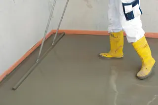 Das Bild zeigt einen Verarbeiter, der eine Schicht Zementschnellestrich glatt auf dem Boden verstreicht.