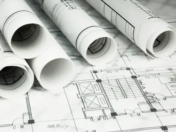 Des plans enroulés de plans d'ensemble et de projets de bâtiments reposent sur un plan déroulé