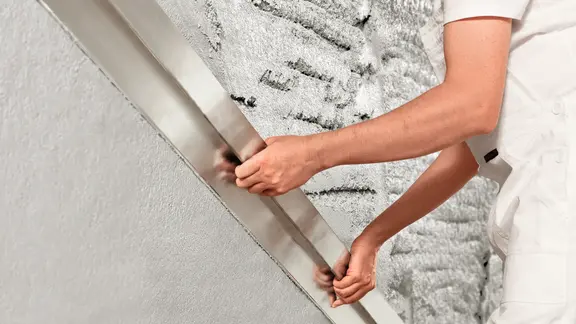 Handwerker bei der Verarbeitung von Putz an einer Wand