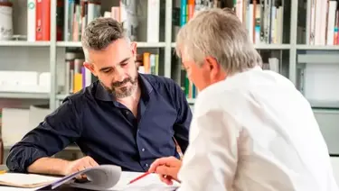 Zwei Personen im angeregten Gespräch mit Bücherregal im Hintergrund