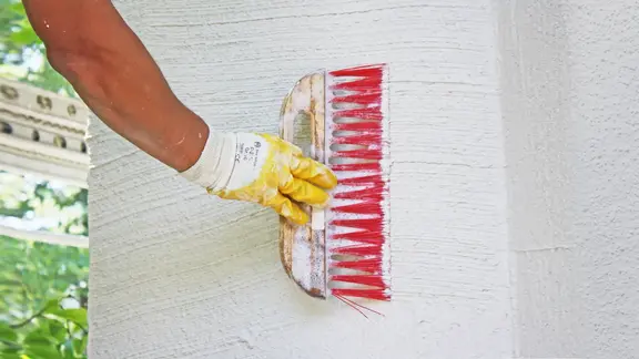 Hand mit Besen streicht die Wand 