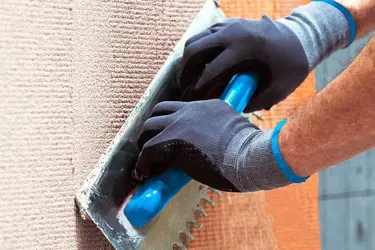 Eine Fassade wird von einem Verarbeiter verputzt.