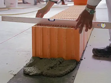 Die Ausrichtung der Steinreihe wird mit Hilfe einer Wasserwaage überprüft