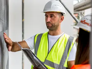 Verarbeiter beim Begutachten einer verputzten Wand