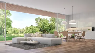 Salon et salle à manger futuristes avec cuisine et grande baie vitrée donnant sur la verdure