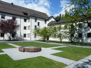 Pelouse symétrique avec fontaine en pierre au centre dans la cour intérieure du monastère de Pfäfers en arrière-plan