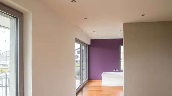 Intérieur avec des murs crépis blancs ainsi qu'un mur aubergine au fond de la baignoire