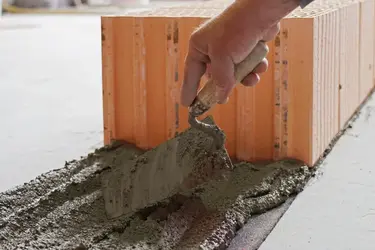Eine Schicht Mauermörtel wird als erste Schicht auf den Boden aufgetragen.