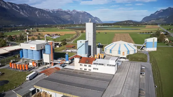 Luftaufnahme des Produktionswerks der Fixit AG in Bex mit Steinhalle, Lagerbereichen und Fixit Silos
