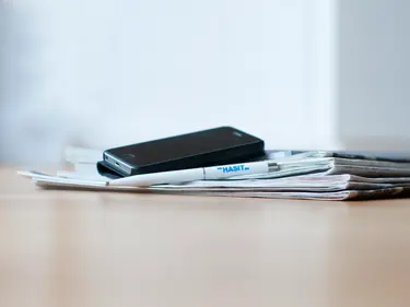 Mehrere Prospekte, darauf ein Handy und ein Stift von HASIT