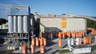 Vue générale de la halle de production Fixit AG Holderbank avec les silos pour camions et les silos Fixit debout en orange