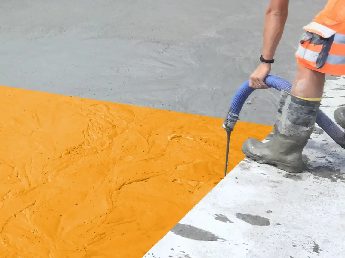 Un ouvrier de chantier coule du béton mousse Fixit POR à l'extérieur, motif promotionnel avec une partie du béton en orange