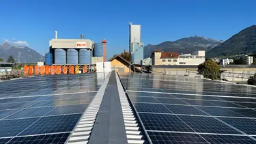 Photovoltaik-Anlage auf einer Lagerhalle am Fixit Standort in der Schweiz mit Silos und der Produktionsgebäude im Hintergrund