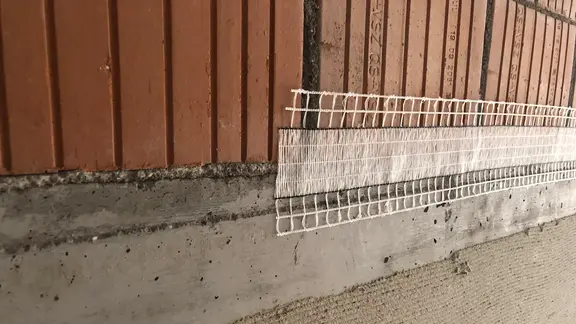 Transition de matériaux entre un mur en béton et une maçonnerie en briques avec la bande de désolidarisation Stucanet® Easy Fix déjà collée.