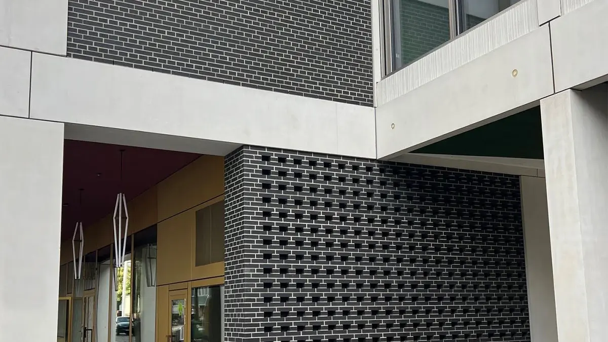 Ansicht der Aussenfassade mit den dunkelgrauen Mauerflächen mit Lochstruktur