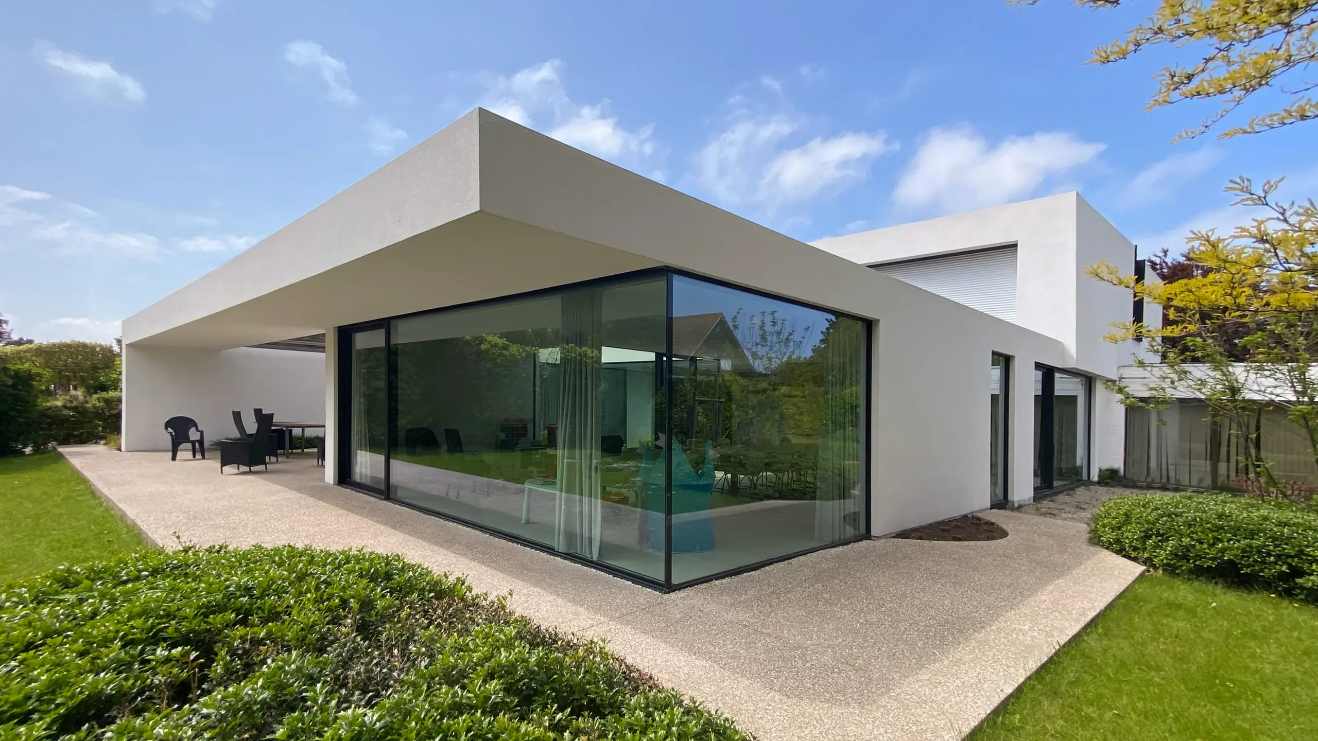 Modernes Einfamilienhaus mit grosser Glasfront und kubistischem Aussehen, weiss verputzt.